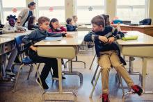 Two boys talk to each other during class at an elementary school.